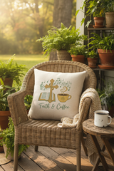 Faith and Coffee decorative pillow on a wicker porch chair with steaming coffee mug and greenery in warm morning light
